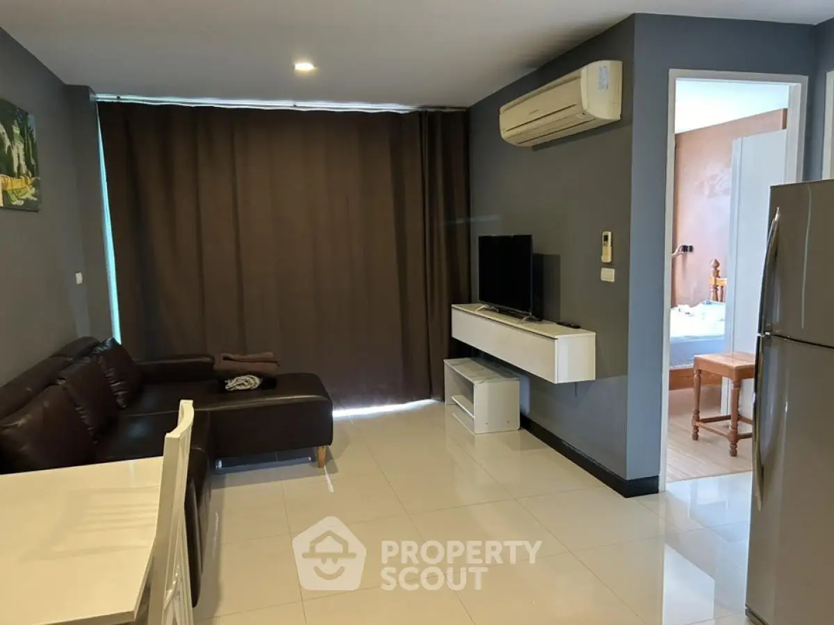 Modern living room with sleek furniture and air conditioning, adjacent to a cozy bedroom.