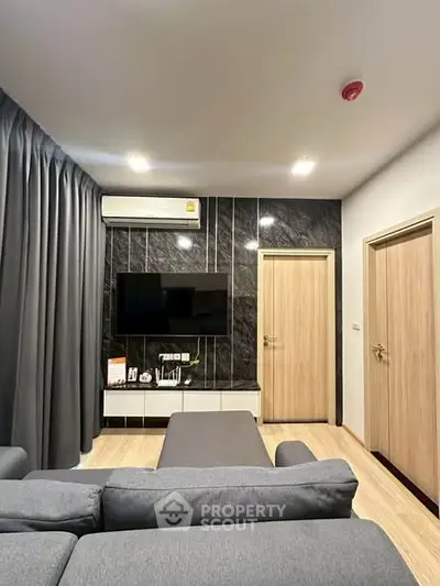 Modern living room with sleek design, featuring a wall-mounted TV and stylish furniture.