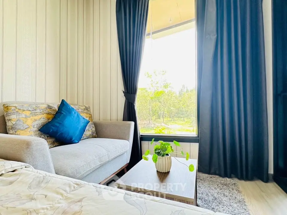 Cozy living room with large window and stylish decor, offering a serene view of nature.