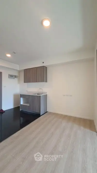 Modern open-plan kitchen with sleek cabinetry and wood flooring in a bright apartment.
