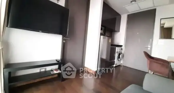 Modern apartment with sleek interior, featuring a wall-mounted TV, washing machine, and stylish furniture.