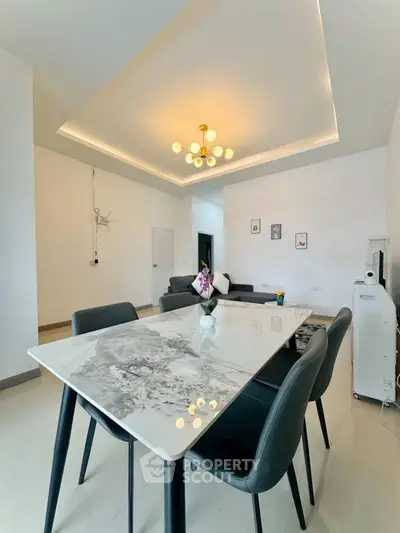Modern dining area with elegant marble table and stylish lighting in open living space.