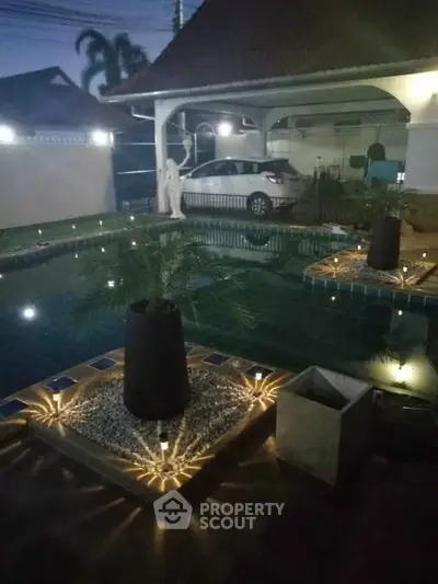 Stunning evening view of a luxurious home with illuminated pool and carport.