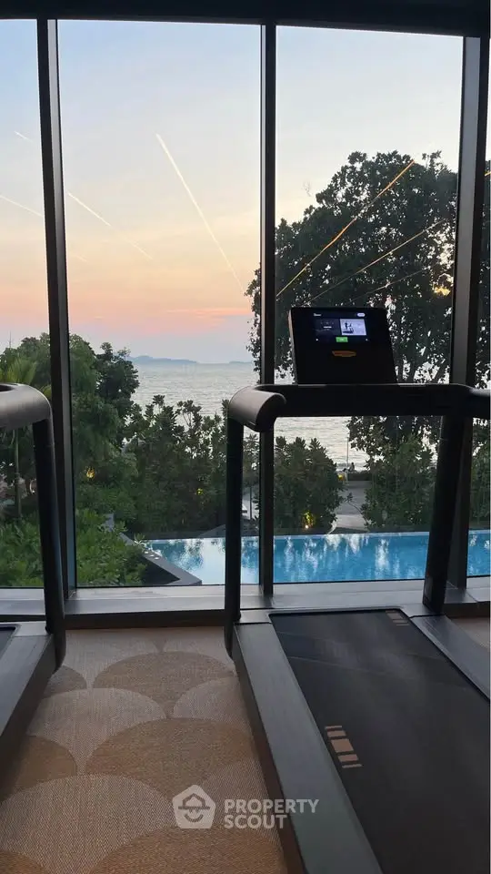 Luxurious gym with stunning ocean view and poolside scenery, perfect for fitness enthusiasts.