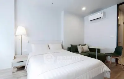 Modern bedroom with cozy seating area and air conditioning in a stylish apartment.