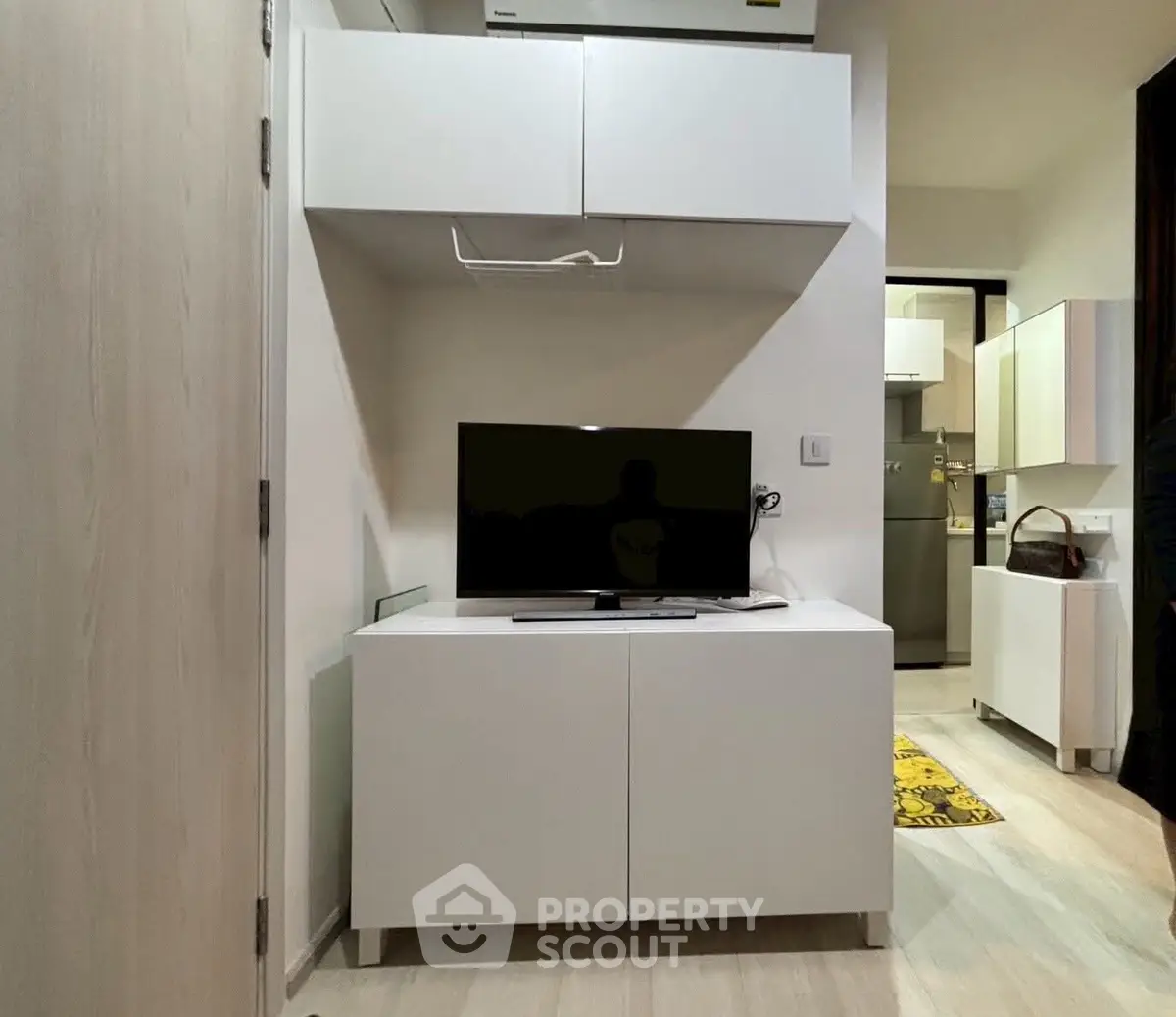 Modern living room with sleek white cabinetry and flat-screen TV, showcasing minimalist design.