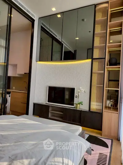 Modern bedroom with sleek design, built-in storage, and open kitchen view.