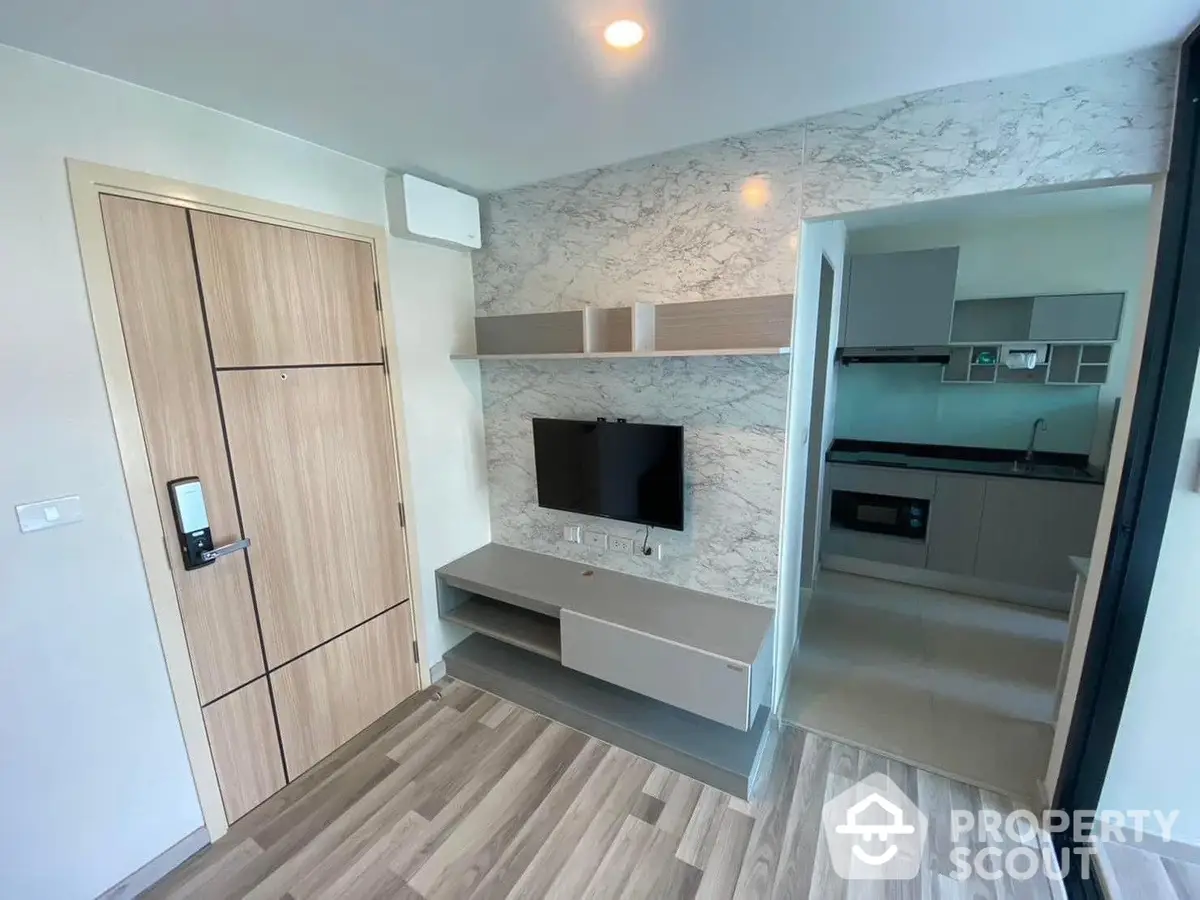 Modern apartment interior with sleek finishes, featuring a combined living and kitchen area, wood-like flooring, and built-in cabinetry.