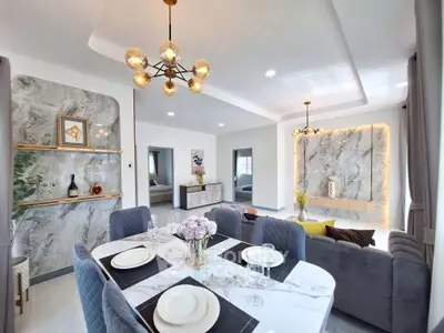 Luxurious open-plan living and dining area with elegant marble accents and modern lighting.