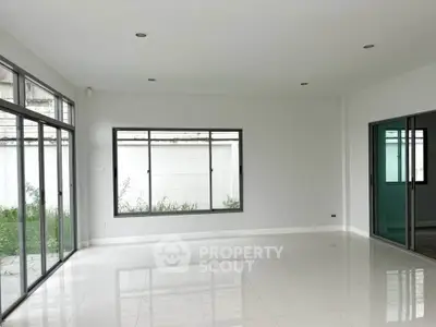 Spacious empty room with large windows and white tiled floor, perfect for customization.