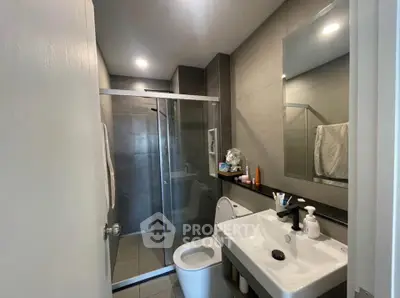 Modern bathroom with sleek design, featuring a glass shower enclosure and contemporary fixtures.