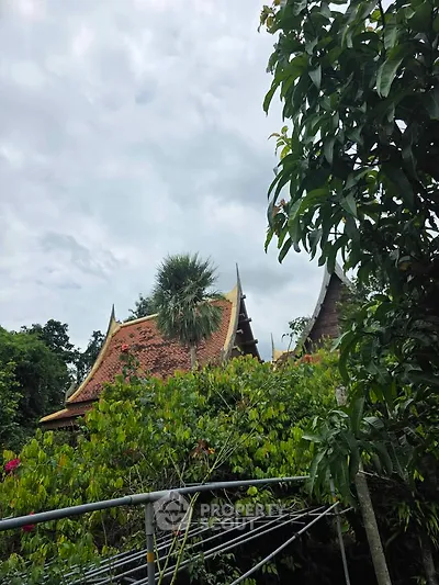 Charming traditional building with ornate roof surrounded by lush greenery, perfect for serene living.