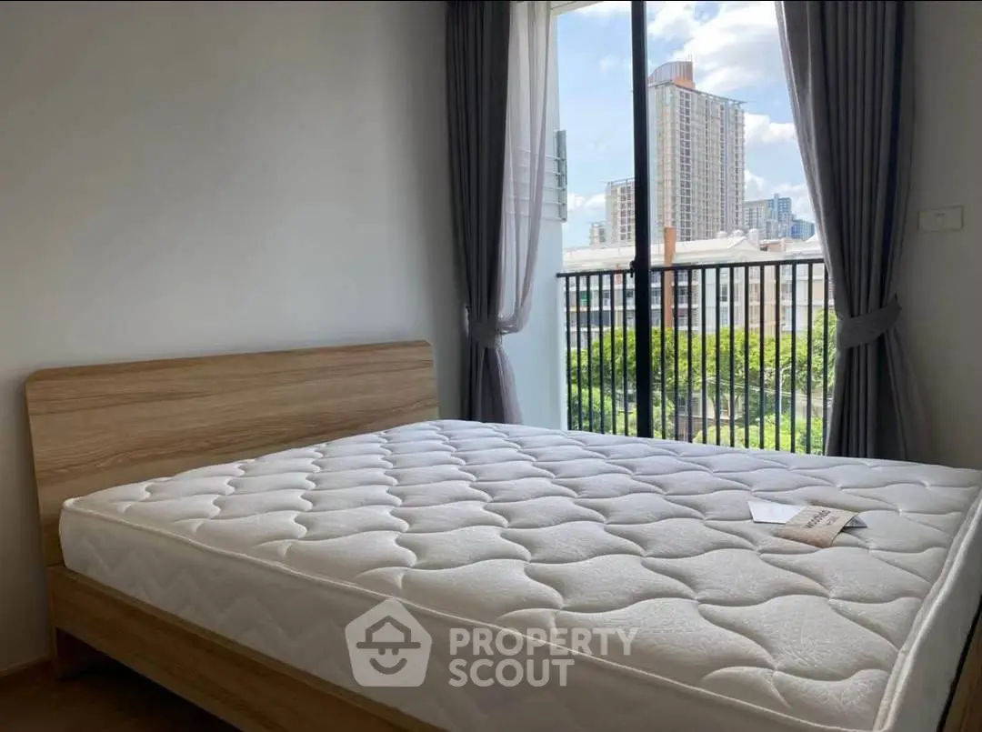 Modern bedroom with large window and city view, featuring a comfortable bed and stylish decor.