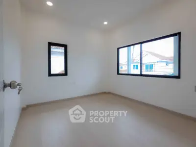 Spacious empty room with large windows and modern lighting, perfect for customization.