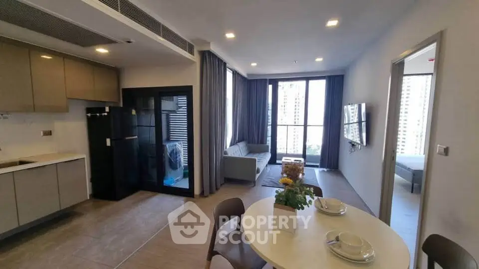 Modern open-layout apartment with stylish kitchen and cozy living area, featuring large windows and city views.