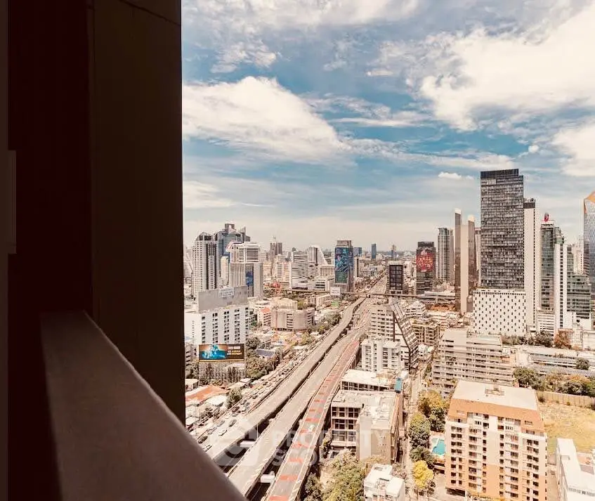 Stunning cityscape view from a high-rise balcony overlooking urban skyline and highway.