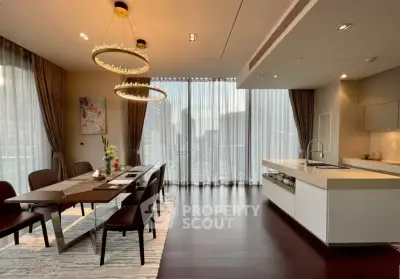 Luxurious open-plan kitchen and dining area with city view, featuring elegant lighting and modern design.