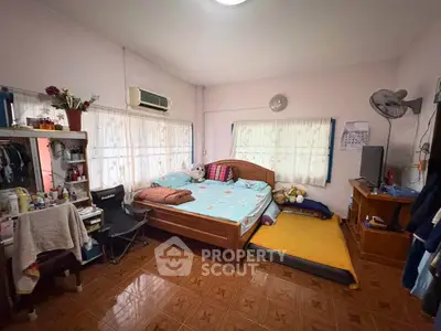 Cozy bedroom with wooden bed, air conditioning, and ample natural light from large windows.