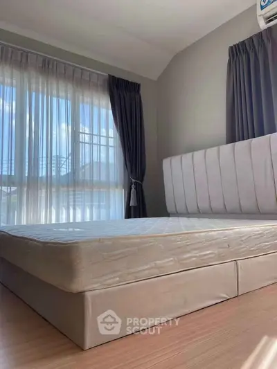 Spacious bedroom with large windows and elegant curtains, perfect for natural light lovers.
