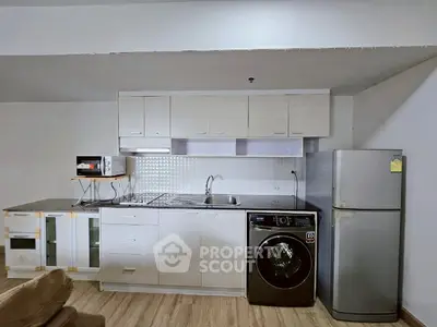 Modern kitchen with washing machine, fridge, and microwave in a compact layout.