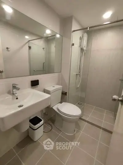 Modern bathroom with sleek fixtures and glass shower enclosure in a contemporary apartment.