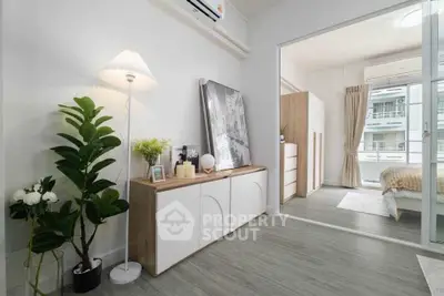 Modern living room with stylish decor and view into a cozy bedroom, featuring elegant furniture and natural light.
