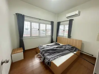 Cozy bedroom with modern design, featuring large windows and air conditioning.