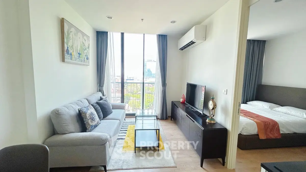 Modern living room with large window and cozy bedroom in open layout apartment.