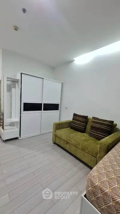 Modern bedroom with stylish green sofa and sleek wardrobe