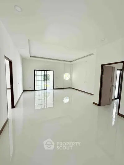 Spacious modern living room with large windows and glossy white flooring.