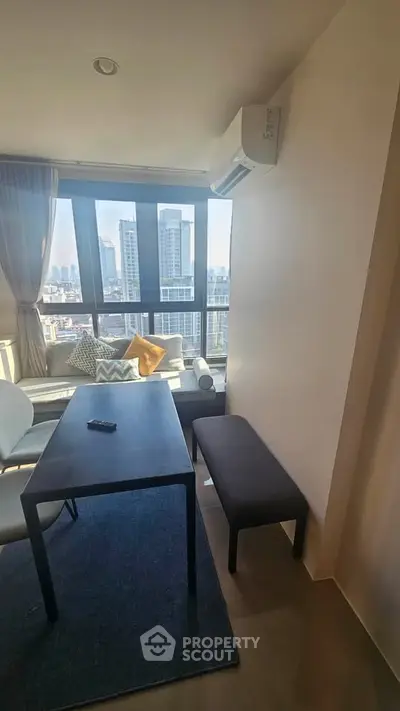 Modern living room with city view, featuring sleek furniture and large windows for natural light.