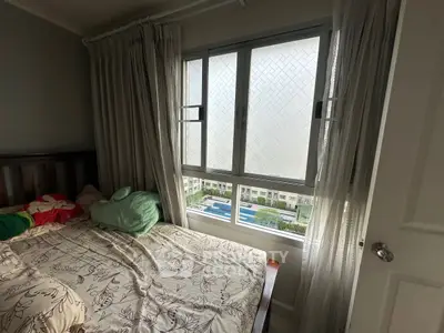 Cozy bedroom with window view of pool and garden in modern apartment