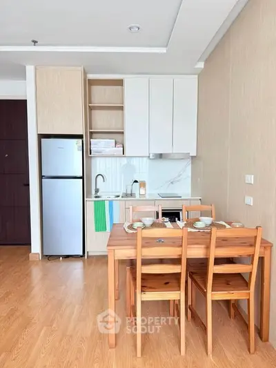 Modern kitchen with wooden dining set and sleek cabinetry in a cozy apartment.