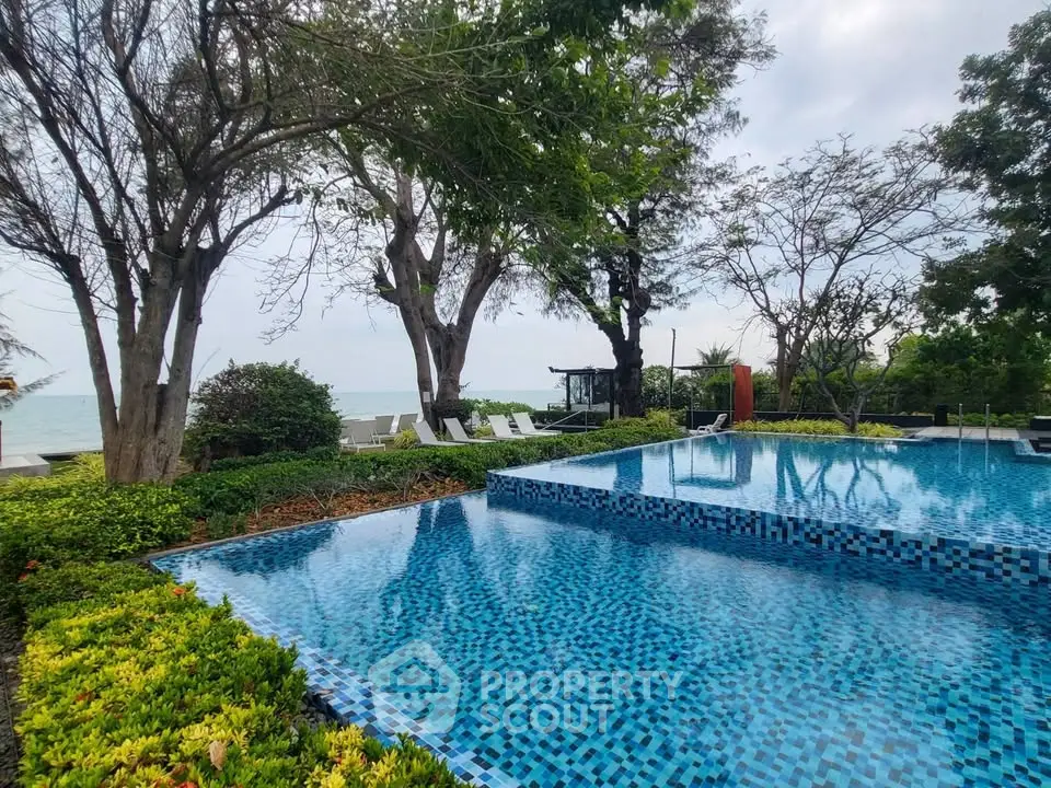Luxurious poolside view with lush greenery and ocean backdrop, perfect for relaxation and leisure.