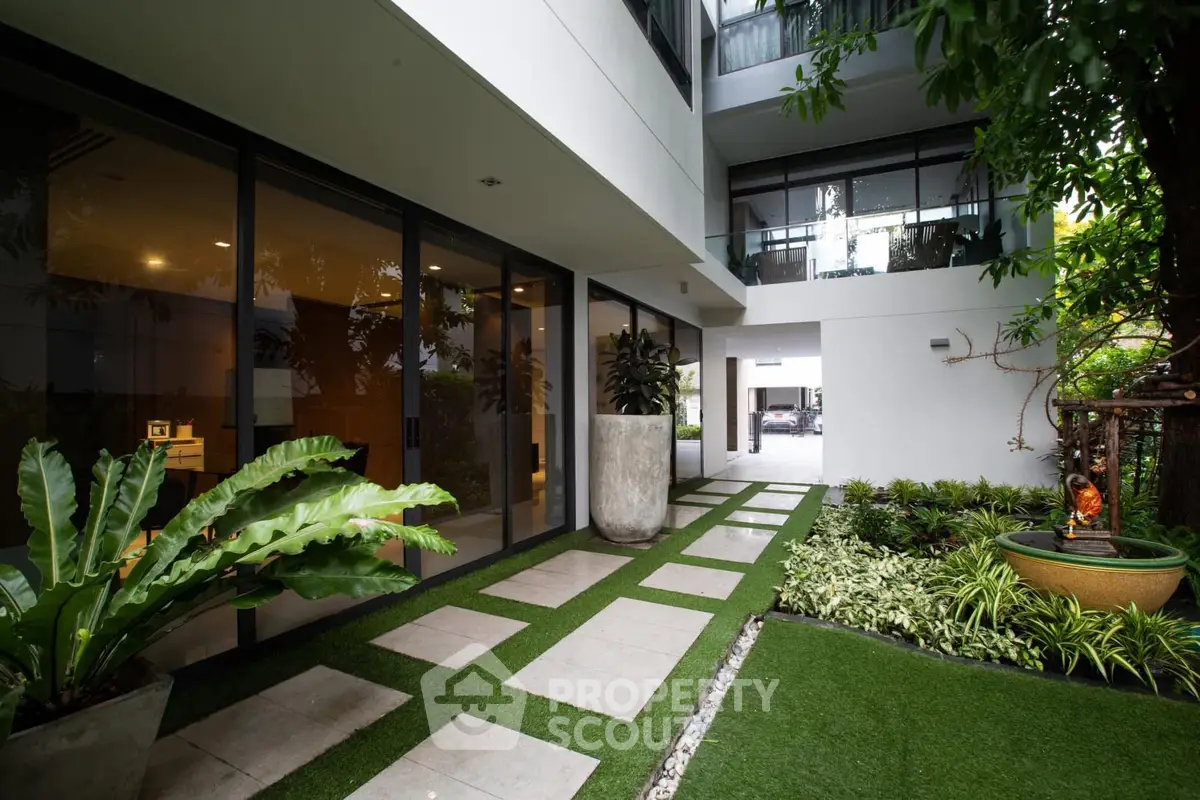 Modern building entrance with lush garden and large windows