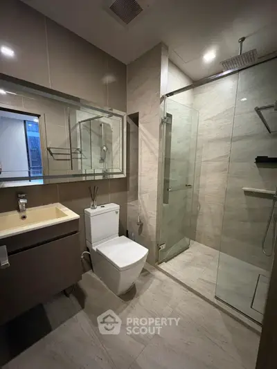 Modern bathroom with glass shower and sleek fixtures in contemporary apartment.