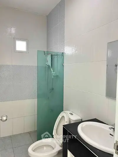 Modern bathroom with glass shower and sleek fixtures in contemporary home.