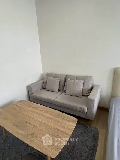Cozy living room with modern gray sofa and wooden coffee table on plush rug.