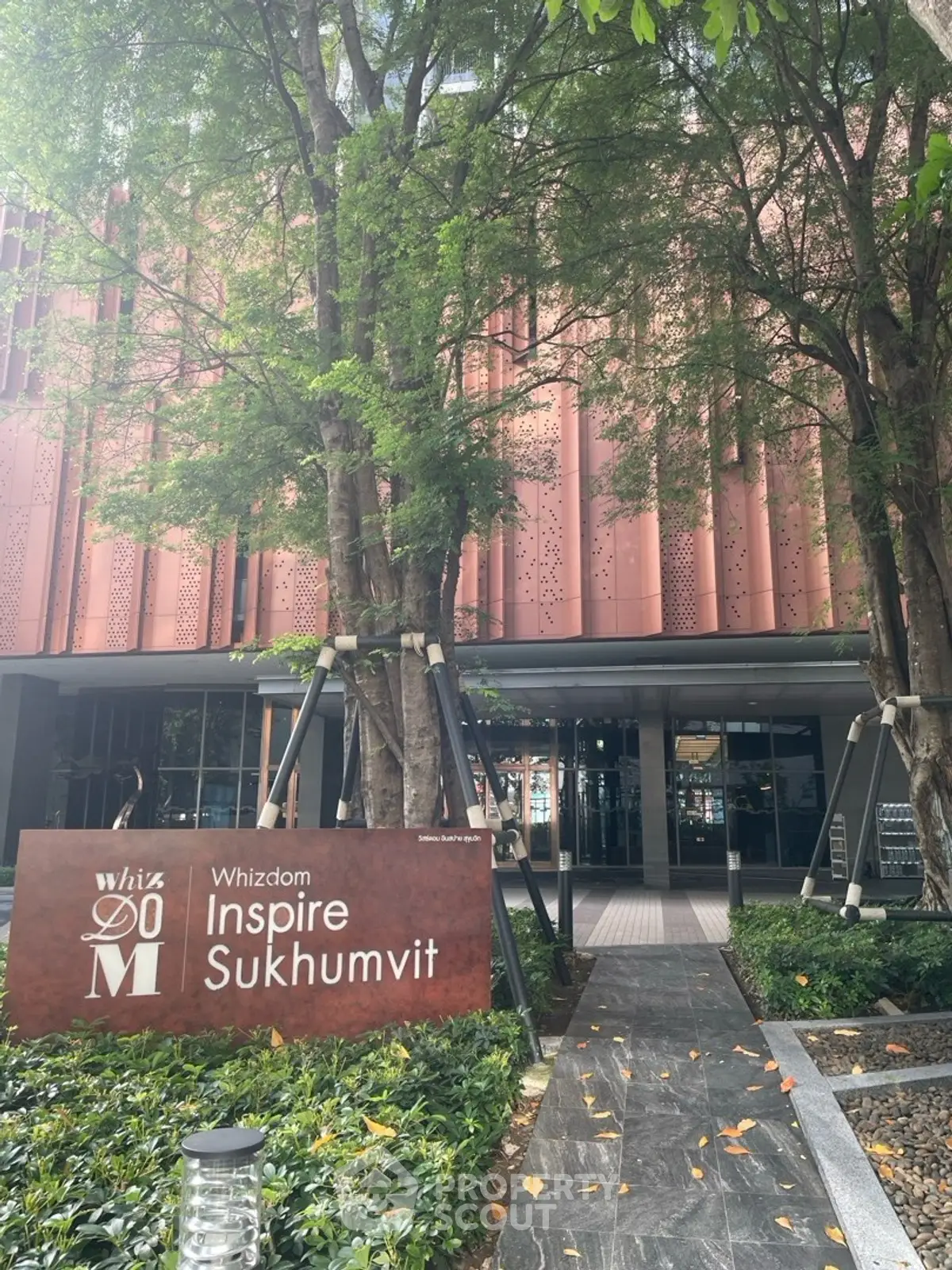 Modern building entrance with lush greenery at Whizdom Inspire Sukhumvit.