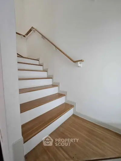 Modern wooden staircase with sleek handrail in minimalist home interior
