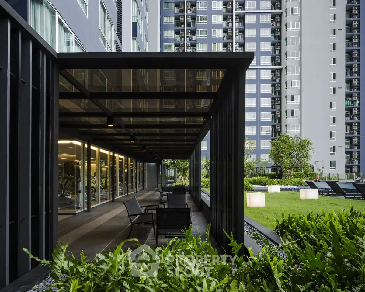 Modern apartment building with lush garden and outdoor seating area, perfect for relaxation.