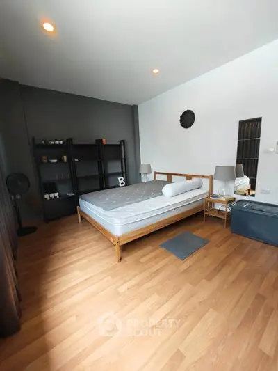 Spacious modern bedroom with wooden flooring and stylish decor