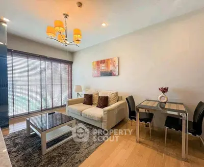 Modern living room with cozy sofa, stylish chandelier, and dining area in open layout apartment.