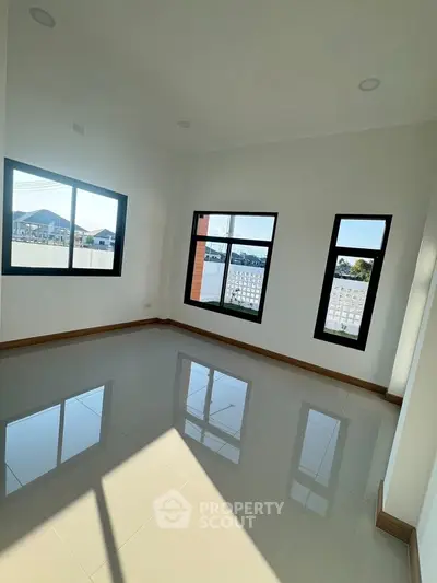 Bright empty room with large windows and glossy tiled floor, offering a modern and spacious feel.