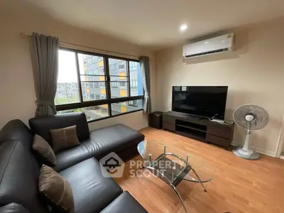 Modern living room with large window, leather sofa, and flat-screen TV.