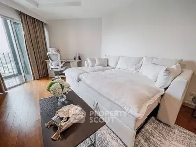 Spacious living room with modern decor and large sofa, featuring a balcony view.