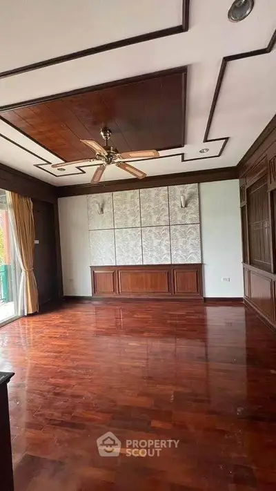 Spacious living room with elegant wooden flooring and ceiling fan, perfect for modern living.
