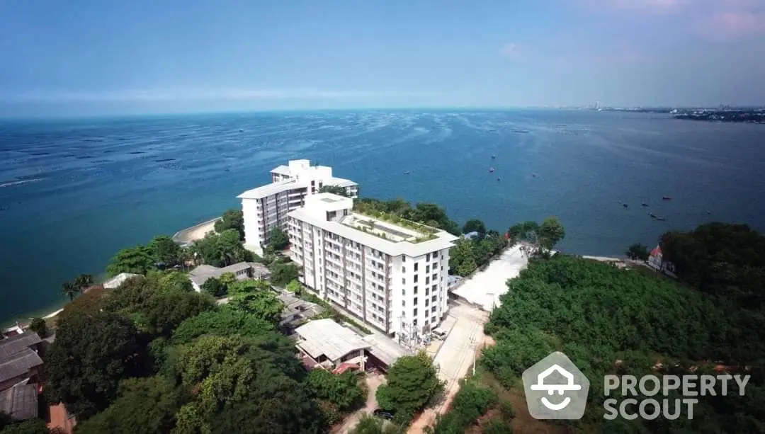 Aerial view of a waterfront high-rise residential building surrounded by lush greenery with panoramic ocean views, ideal for serene coastal living.