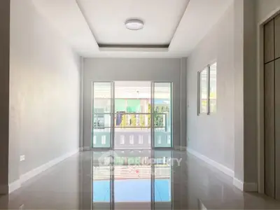 Spacious unfurnished living room with glossy floors and large windows offering natural light.