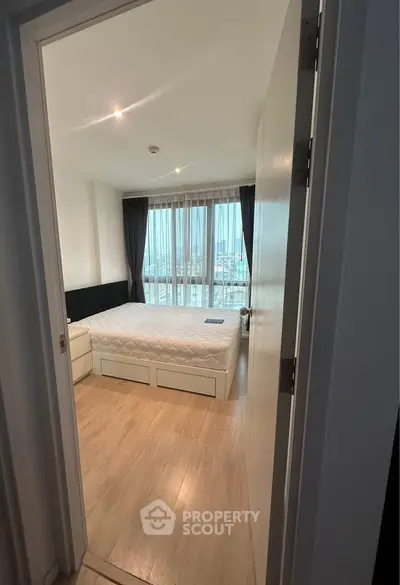 Spacious bedroom with large windows offering a stunning city view, featuring modern furnishings and ample natural light.